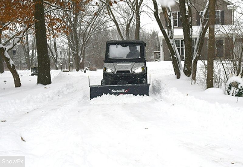 UTV With a Fully Enclosed Cab, Fitted With a SnowEx Snow Plow With a Swath of Cleared Snow In its Wake