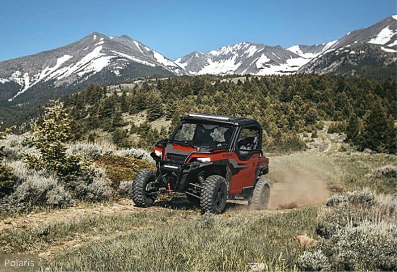 Red and Black UTV Driving on a Dusty Trail Through a Mountainous High Altitude Landscape, During Late Spring