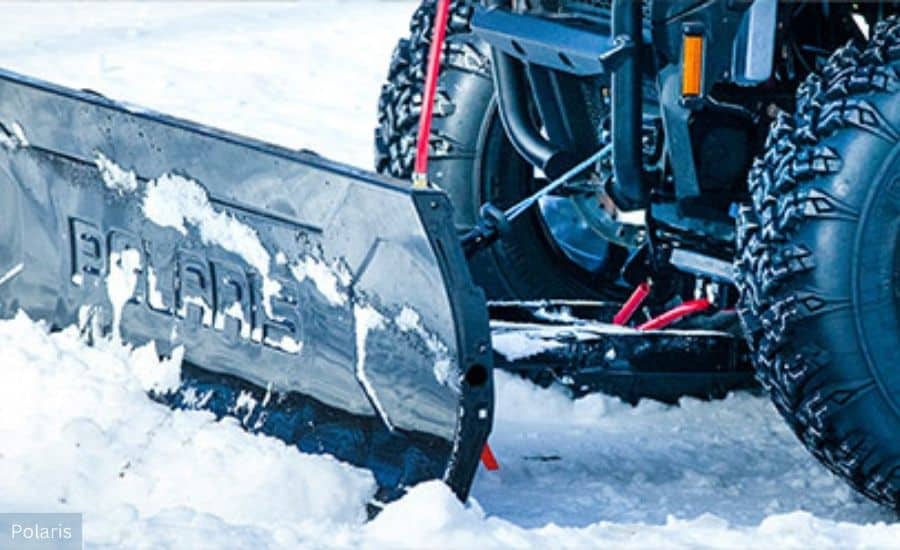 Black Polaris branded snow plow attachment on the front of a UTV.