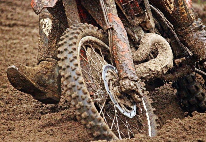 Close-up of a Dirt Bike's Front Wheel Heavily Coated in Mud