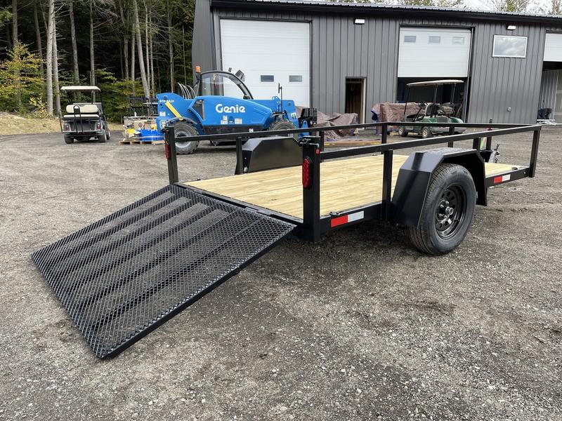 Single Axle Utility Trailer With a Black Frame and Wooden Bed Parked on a Gravel Lot