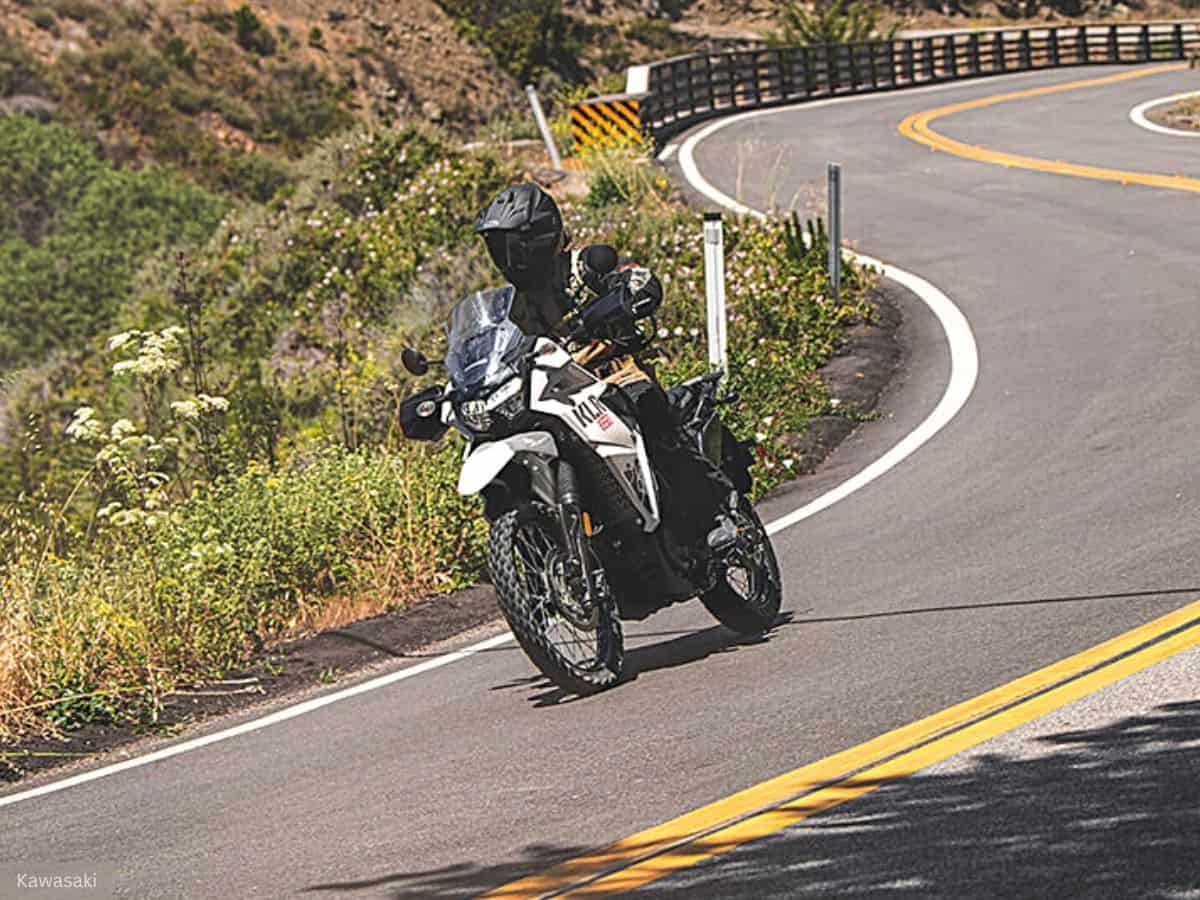 Motorcyclist in All-black Gear and a Full-face Helmet Riding a Kawasaki KLR 650 on a Scenic Mountain Road