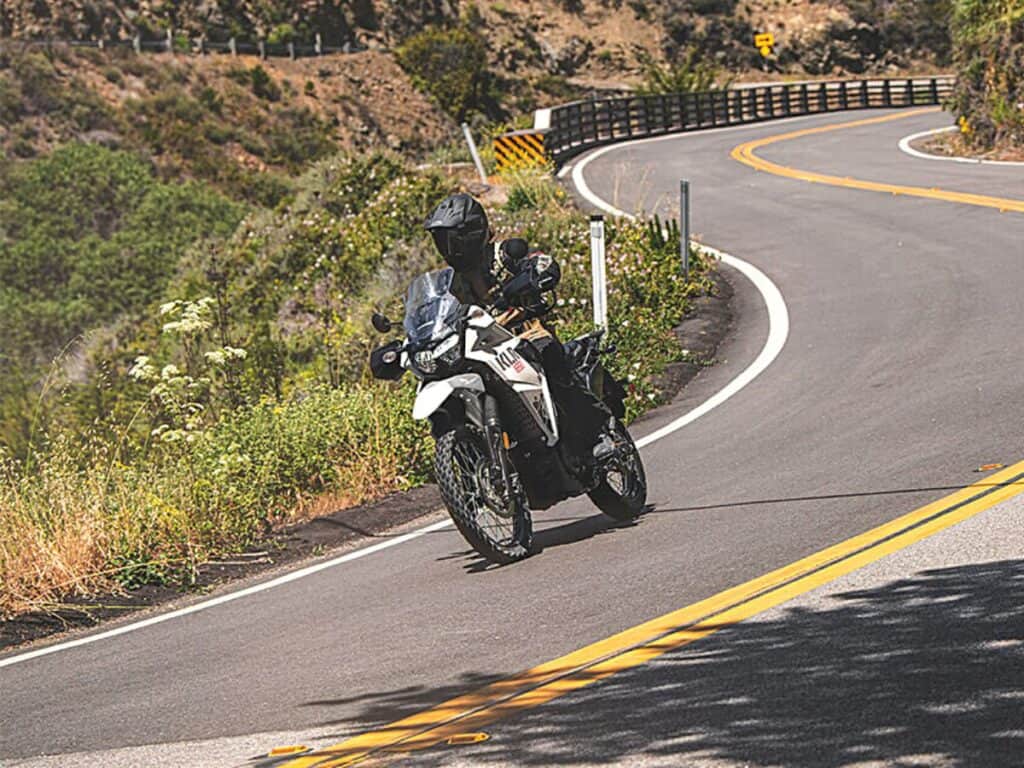 Motorcyclist in All-black Gear and a Full-face Helmet Riding a Kawasaki KLR 650 on a Scenic Mountain Road