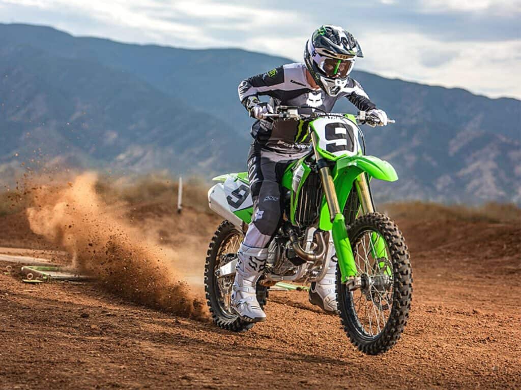 Motocross Rider, Numbered 9, Aggressively Accelerating on a Kawasaki KX450, Kicking Up a Cloud of Dust on a Dirt Track