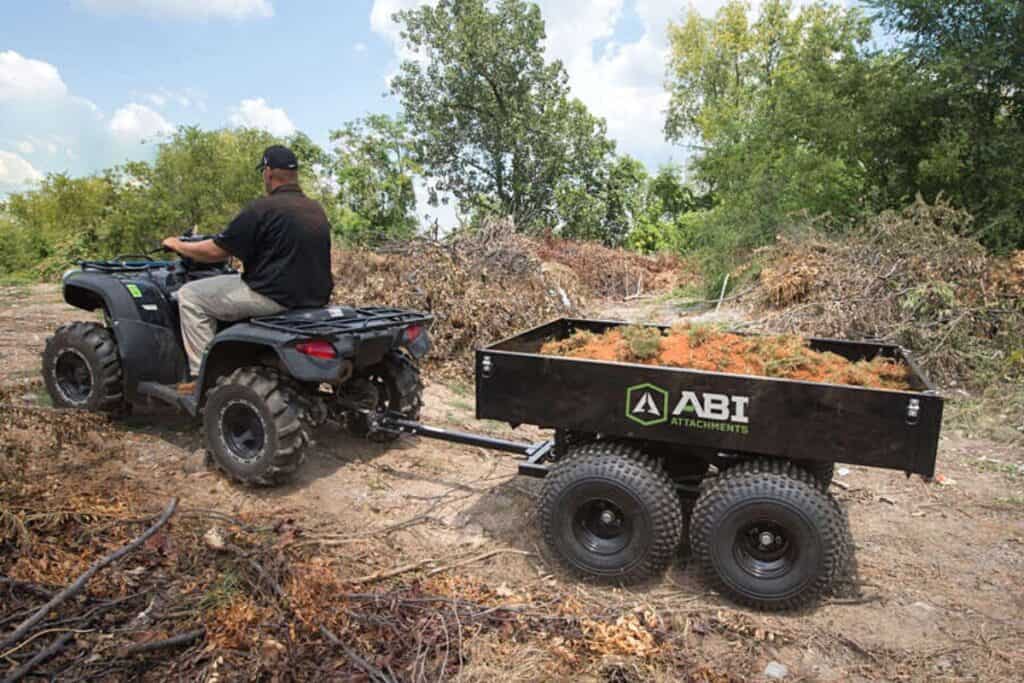 ATV Equipped with a Dual-Axle Trailer Filled with Brush and Debris, Being Driven Through a Wooded Area