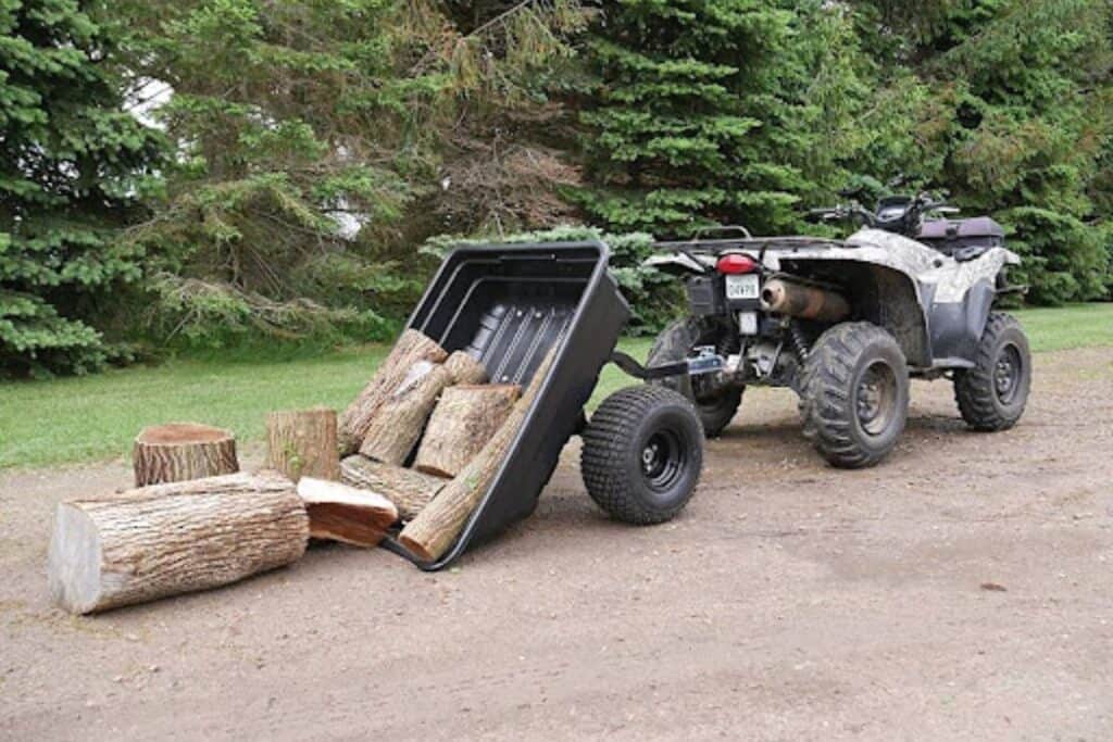 ATV with Tilted Dump Trailer Behind it, Unloading Logs onto the Ground