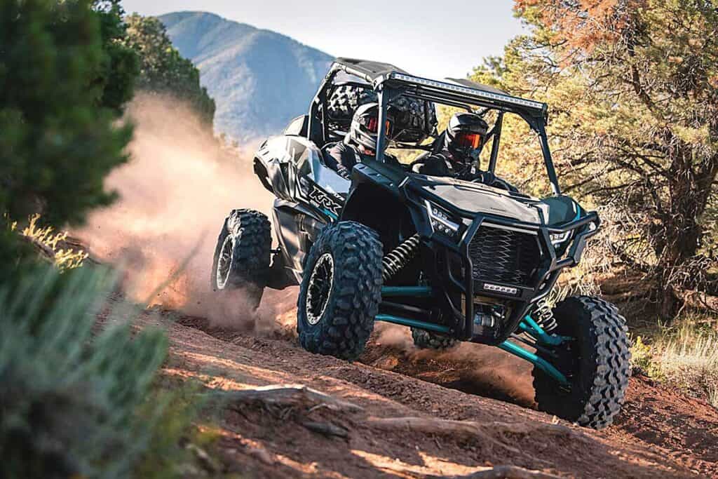 Kawasaki Teryx KRX 1000 UTV Maneuvering on a Rugged Dirt Trail Flanked by Dense Foliage