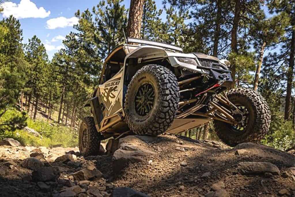 Arctic Cat Wildcat XX Black Hills Edition Side-By-Side Navigating a Challenging, Rocky Trail in a Forest Setting