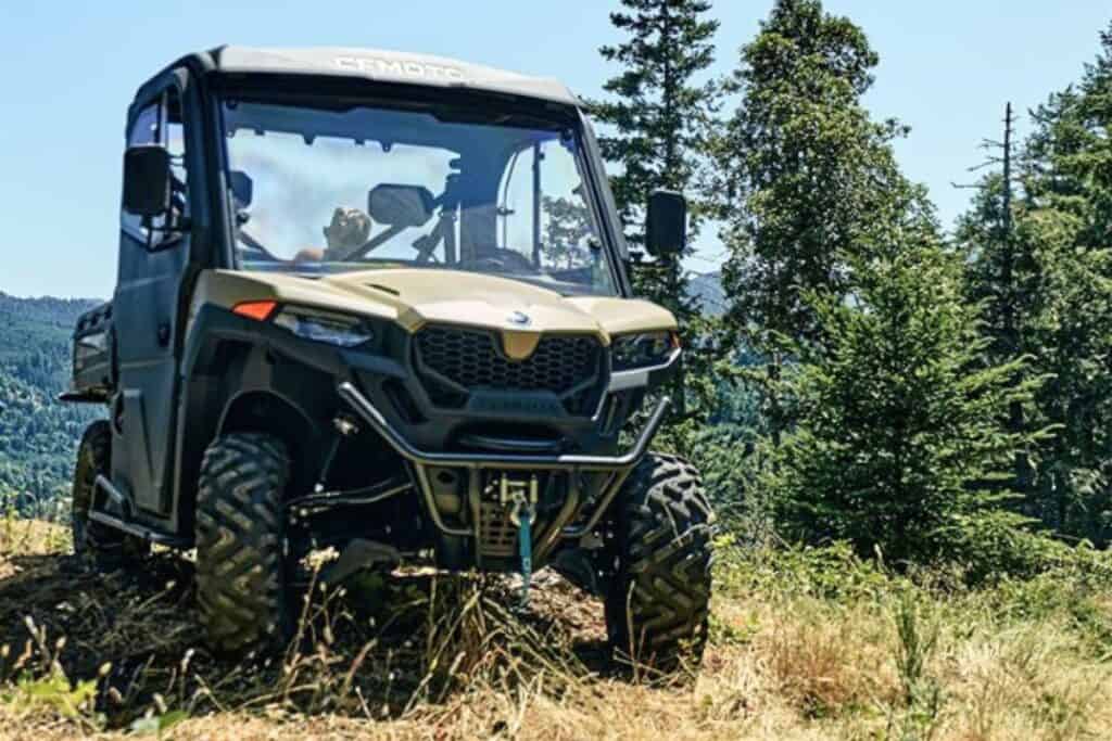 A CFMoto UForce 600 UTV parked in a mountainous forest landscape.